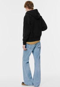 Fekete, kapucnis cropped kapucnis pulóver, nyers szegéllyel. Világoskék, bővülő farmerszoknyával párosítva. Az anyag puha és laza.