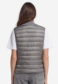 Szary bezrękawnik puchowy z poziomym przeszyciem, żeberkowym dekoltem i gładką fakturą, noszony na białej koszulce.