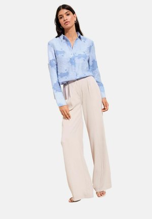 Light blue button-up shirt with a textured, cloud-like pattern, paired with wide-leg beige pants. The outfit features long sleeves.