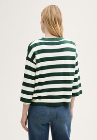 Gestreifter Pullover mit grünen und weißen horizontalen Streifen, lockerer Schnitt, Rundhalsausschnitt und Dreiviertelärmeln, kombiniert mit blauen Jeans.