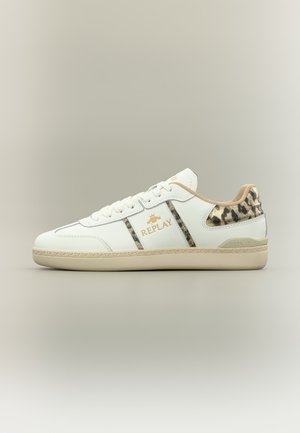 Baskets basses blanches avec semelle beige, talon imprimé léopard et rayures, logo doré « Replay » sur le côté.
