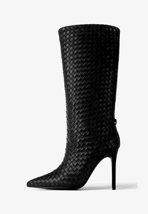 Schwarze, geflochtene Lederstiefelette mit hohen Absätzen und spitzem Fuß, ausgestattet mit einem hohen Schaft und glatter Textur, ergänzt durch einen eleganten Stilettoabsatz.