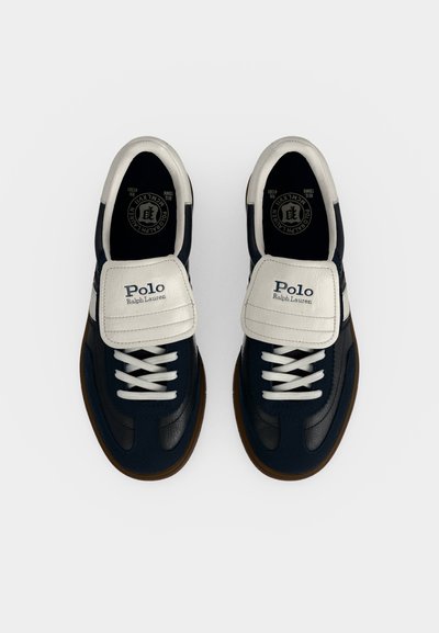 Ζευγάρι μπλε-σκούρο και λευκά sneakers Polo Ralph Lauren με κορδόνια και λογότυπα στις γλώσσες, σε απλό φωτεινό φόντο, από πάνω.