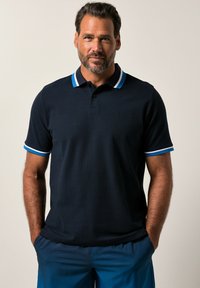 Navy polo shirt with contrasting striped collar and sleeve trim. Features three buttons and a subtle logo on the chest. Made of textured fabric.