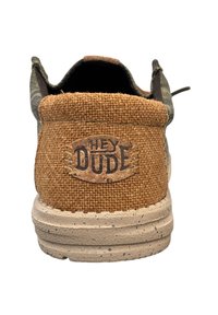 Scarpa basse con tallone in tessuto intrecciato marrone, parte superiore in camouflage grigia, dettagli in sughero naturale e suola beige maculata. Logo "HEY DUDE" visibile.