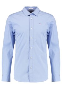 Camisa de vestir de manga larga en azul claro, confeccionada en algodón. Presenta un collar puntiagudo, cierre de botones en la parte frontal y un pequeño logo en el lado izquierdo del pecho.