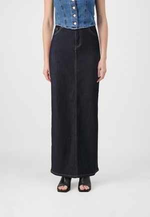 Dark denim maxi skirt with a straight cut, featuring contrast stitching and a high waist. Worn with black open-toe heeled sandals.
