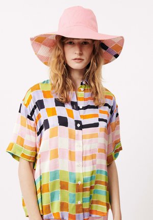 Chemise à motifs quadrillés aux teintes pastel, multicolore, avec un chapeau rose à larges bords, mettant en avant un tissu léger.