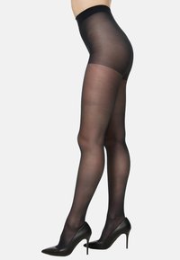 Czarne prześwitujące rajstopy o gładkiej fakturze, z wysokim pasem i wzmocnionymi palcami. Noszone z czarnymi butami na wysokim obcasie.