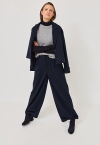 Blazer de rayas marineras combinado con un suéter gris claro, pantalones anchos navy y botines negros; textura suave y diseño a medida.