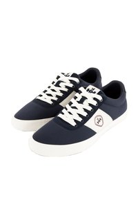 Sneakers in tela navy con accenti bianchi, dotati di lacci bianchi e una patch con logo. La suola è in gomma bianca con un motivo testurizzato.