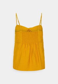 Žlutý top bez rukávů s nabranou strukturou, nastavitelné špagetové ramínka a uzlový detail na zádech. Hladká tkanina s volným střihem.