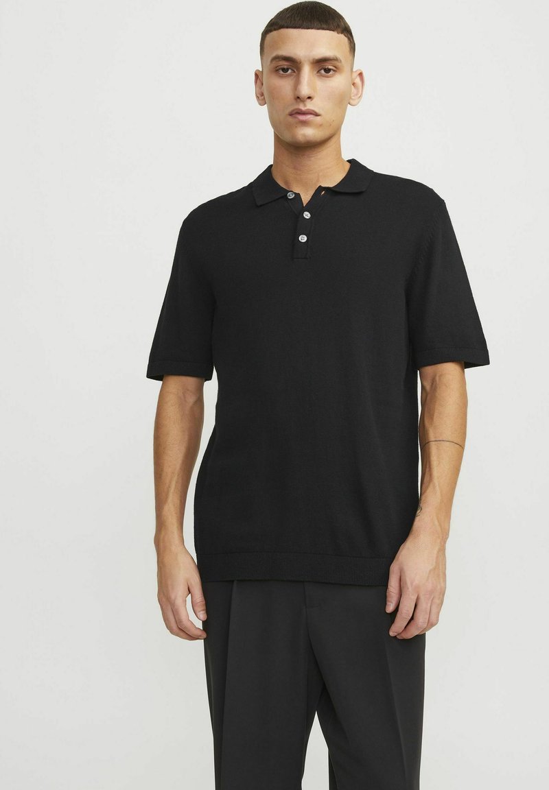Černé polo tričko s krátkým rukávem vyrobené z pletené tkaniny. Má límečkový design, zapínání na tři knoflíky a žebrované lemy a rukávy.