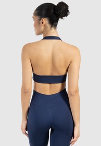 Marinblå sportbehå med halterneck, ryggutskärning och slät yta. Kombinerad med matchande högmidjade leggings.