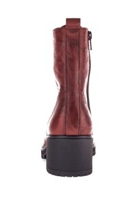 Bottine en cuir marron avec une finition texturée, fermeture zippée à l'arrière et un talon bloc solide. Design épuré avec des détails de couture minimaux.