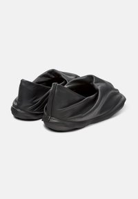 Pantofole in pelle nera con un design superiore increspato, texture morbida e retro chiuso. Forma minimalista con suola flessibile.