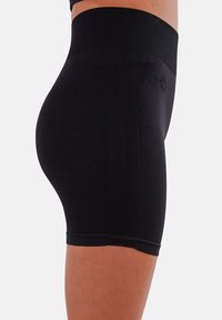 Pantaloni corti neri a compressione con un tessuto liscio, una cintura ampia e dettagli ribattuti sui lati per un tocco di texture. Progettati per una vestibilità aderente.