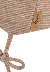 Soft knit beige and light brown striped fabric with a small leather tag labeled "Strandlä" and a tied cord.