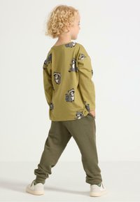 Oliven grøn langærmet skjorte med vaskebjørntryk, parret med grønne sweatpants. Sættet er lavet af blødt og komfortabelt stof.