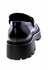 Scarpa nera in vernice con suola spessa e chunky e fondo con battistrada, mostrata da un angolo posteriore su sfondo bianco.