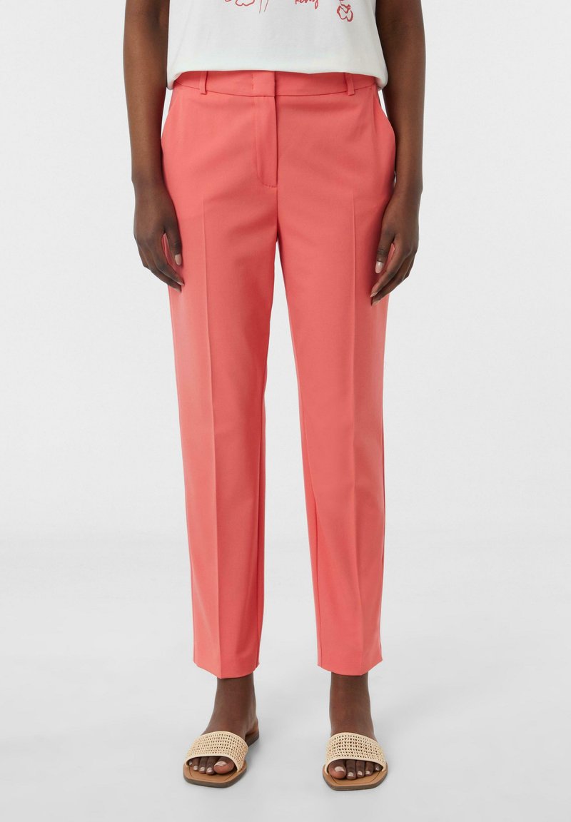 Koraal kleurige taillepantalons met een rechte pasvorm, platte voorkant en twee zijzakken. Gecombineerd met lichtbruine geweven instapsandalen.