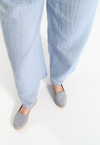 Szare zamszowe espadryle o falbaniastych brzegach, połączone z jasnoniebieskimi, teksturowanymi spodniami o szerokich nogawkach. Podeszwę zdobi plecionka z juty.