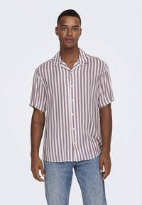 Trumpomis rankovėmis marškiniai su sagomis, vertikaliomis bordo ir baltomis juostelėmis. Turi smailų apykaklę ir lengvą audinį, pateikti su mėlynais džinsais.