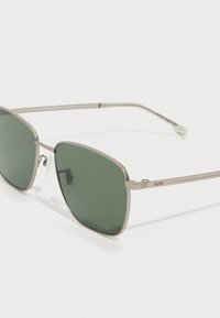 Λεπτά γυαλιά ηλίου με μεταλλικό πλαίσιο, πράσινους φακούς και ρυθμιζόμενα στήριγματα για τη μύτη, με το λογότυπο "BOSS" στην πλευρά.