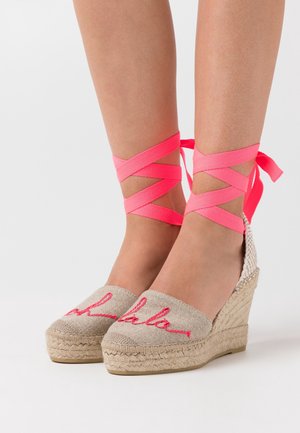 Alpargatas cuña de tela beige con texto bordado en rosa; cuenta con cintas de raso rosas entrelazadas alrededor del tobillo y suela de yute texturizada.