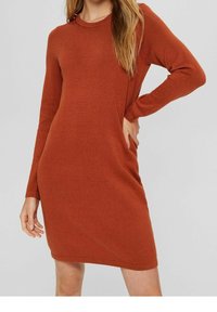 Robe en tricot couleur rouille avec des manches longues, un col rond et des poches latérales. Texture lisse et silhouette ajustée. Détails de design minimalistes.