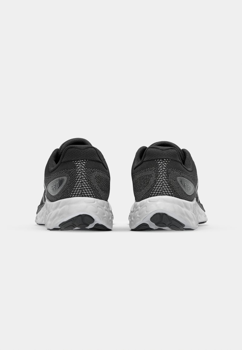 Zapatillas deportivas negras con parte superior de malla texturizada, cuello acolchado y una entresuela blanca con suelas de goma negra. Presenta un logo en el costado.