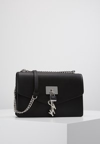 Borsa a tracolla in pelle nera con chiusura a pattina, accessori in argento e tracolla a catena rimovibile. Presenta un charm con logo e una texture liscia.