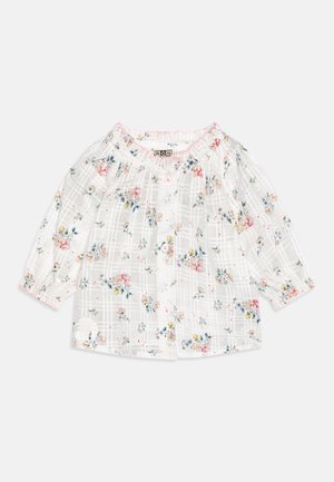 Biała bluzka w kratkę z wielokolorowym kwiatowym wzorem. Posiada marszczony dekolt oraz długie rękawy z elastycznymi ściągaczami.