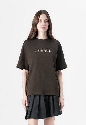 Bruine katoenen T-shirt met korte mouwen en een ronde hals, met in het midden van de borst witte tekst "FEMME". Eenvoudige, relaxte pasvorm.