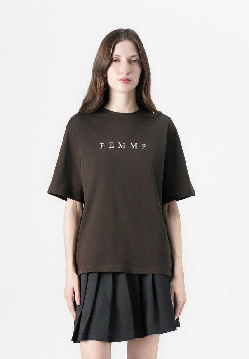 Bruine katoenen T-shirt met korte mouwen en een ronde hals, met in het midden van de borst witte tekst "FEMME". Eenvoudige, relaxte pasvorm.