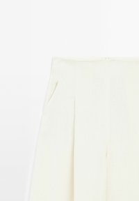 Spodnie w kolorze kremowym, wykonane z mieszanki lnu, z wysokim stanem, z bocznymi kieszeniami i plisami z przodu, zapewniające wykonaną z wyraźnych linii formę i gładką teksturę.