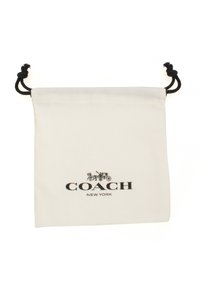 White cotton drawstring bag featuring a black "COACH NEW YORK" logo and graphic of a carriage. Black drawstring detail at the top.