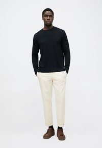 Dunkelblauer Rundhals-Pullover, cremefarbene Hose und braune Sneakers. Einfaches Design mit strukturiertem Strick und leichtem Stoff. Minimalistischer Stil.