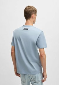 T-shirt di cotone azzurro chiaro con maniche corte, scollatura a girocollo e un'etichetta nera sul retro; texture liscia e vestibilità comoda.