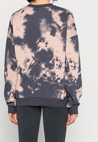 Felpa oversize con motivo tie-dye grigio scuro e rosa, colletto a giro, polsini e orlo a coste, caratterizzata da una texture morbida.