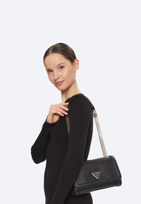 Borsa a tracolla nera con finitura testurizzata, dotata di un'accento logo triangolare e di una tracolla in catena argentata. Design strutturato, dimensioni compatte.