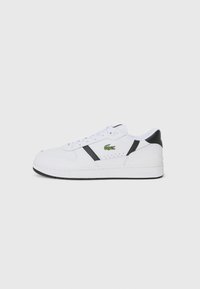 White athletic sneaker with black accents, lace-up design, perforated sections, and a green Lacoste logo on the side. Textured rubber sole.
