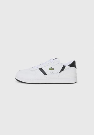 White athletic sneaker with black accents, lace-up design, perforated sections, and a green Lacoste logo on the side. Textured rubber sole.
