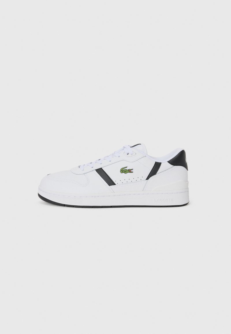 White athletic sneaker with black accents, lace-up design, perforated sections, and a green Lacoste logo on the side. Textured rubber sole.