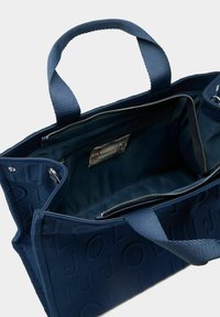 Tumesinine kangast kandekott reljeefse logoga, kahe tugeva sangaga ja sees tõmblukuga taskutega turvaliseks hoiustamiseks.