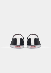 Czarne sneakersy wsuwane z białymi akcentami, z teksturowaną powierzchnią, solidną gumową podeszwą i detalem logo na pięcie.