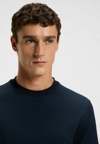 Navy blue textured shirt with a round collar, featuring a subtle pattern and long sleeves, close-fitting design, plain fabric without embellishments.