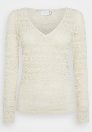 Top din dantelă cu mâneci lungi, crem, având decolteu în V. Prezintă o textură cu model, cu benzi alternante de design floral și geometric.