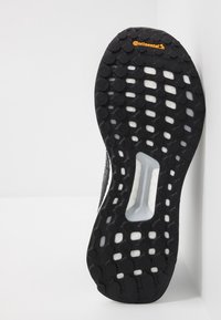 Semelle de sneaker noire en caoutchouc avec un motif texturé de poignées circulaires et ovales ; présente une section blanche au milieu ; marquée "continental".