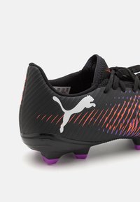 Black football boot with contrasting red and purple diagonal lines, featuring a white logo and purple studs on the sole. Textured finish.